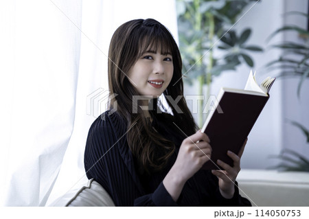 休日にソファで読書する若い女性 114050753