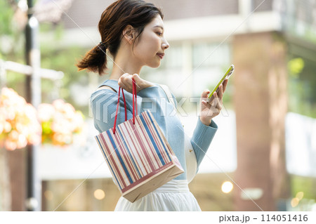 スマホを持ってショッピングをする若い女性 114051416