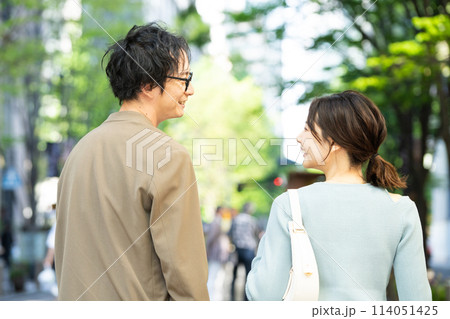 笑顔で街を歩く若いカップルの後ろ姿 笑顔で街を歩く若いカップルの後ろ姿 114051425
