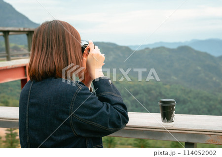solo asian woman hipster traveler taking photo to mountain at outdoor bar of coffeeshop 114052002