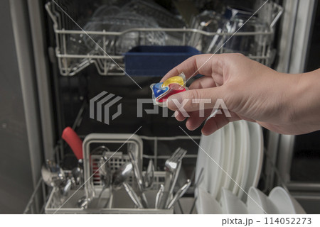 Woman putting detergen kapsul into open dishwasher 114052273