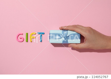 The word "gift" is made of colored plasticine, laid out on a pink background. The word "gift" is made of colored plasticine, laid out on a pink background. 114052767