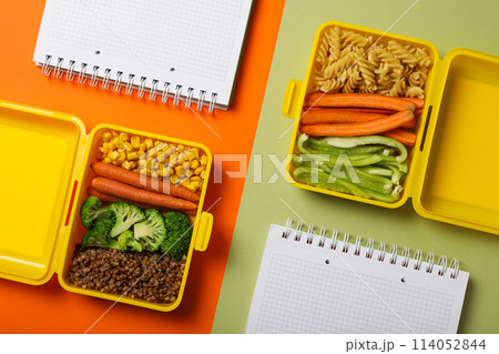 Yellow lunch box with healthy food and notebooks Yellow lunch box with healthy food and notebooks 114052844