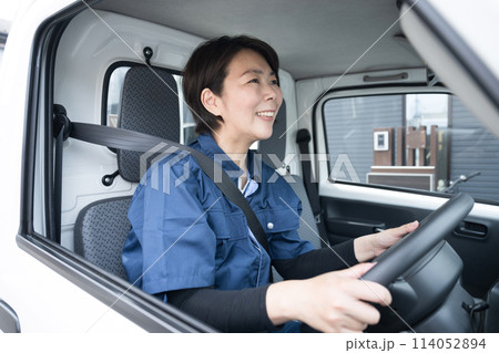 トラックを運転する中年の作業着のガテン系の女性 運送や配送業などのイメージ トラックを運転する中年の作業着のガテン系の女性 運送や配送業などのイメージ 114052894