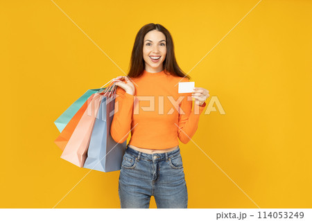Young woman with paper bags and card on yellow background Young woman with paper bags and card on yellow background 114053249
