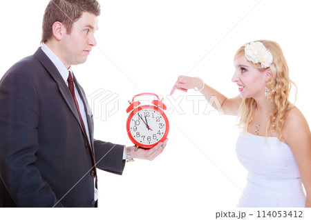 Groom holding big red clock yelling and bride 114053412