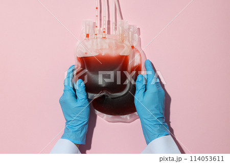Bags with donor blood in doctor's hands on pink background, top view Bags with donor blood in doctor's hands on pink background, top view 114053611
