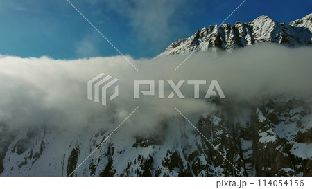 Flying through clouds between mountains 114054156