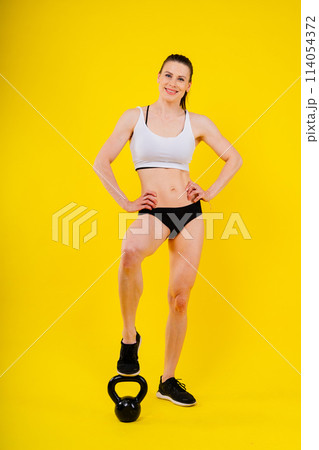 Sport, active lifestyle concept. Smiling strong and slim fitness female athlete holding kettlebell 114054372