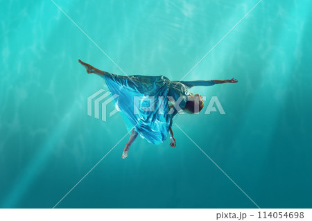 Lost in the current. Young redhead woman in elegant, tender white dress drowning into cyan water, deep ocean with sunlight Lost in the current. Young redhead woman in elegant, tender white dress drowning into cyan water, deep ocean with sunlight 114054698