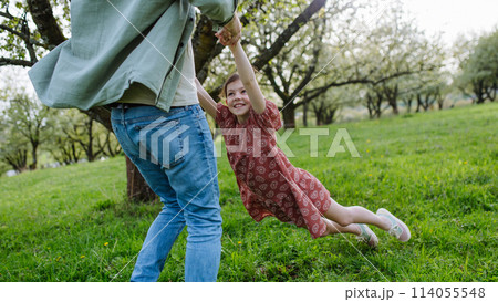 Father spinning daughter around, holding her under armpits. Dad and girl having fun, laughing outdoor. Father's day concept. Father spinning daughter around, holding her under armpits. Dad and girl having fun, laughing outdoor. Father's day concept. 114055548