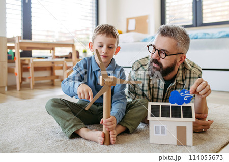 Father explaining renewable energy, teaching about sustainable lifestyle his young son. Playing with house with solar panels, wind turibine at home. Father explaining renewable energy, teaching about sustainable lifestyle his young son. Playing with house with solar panels, wind turibine at home. 114055673
