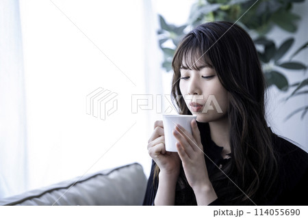 ソファでコーヒーを飲む若い女性 ソファでコーヒーを飲む若い女性 114055690