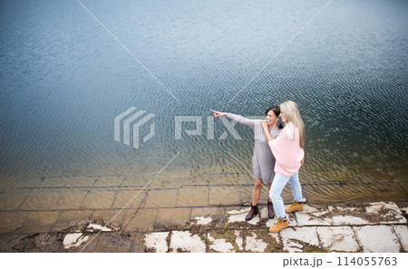 Adult daughter spending time with her mother. Mom and daughter outdoors, on walk by reservoir, lake embankment. Unconditional, deep maternal love, Mother's Day concept.. Adult daughter spending time with her mother. Mom and daughter outdoors, on walk by reservoir, lake embankment. Unconditional, deep maternal love, Mother's Day concept.. 114055763