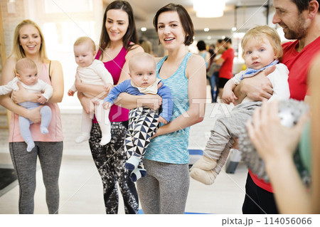 Group exercise class, mother working out with baby in gym. Moms staying active while boding with babies. Group exercise class, mother working out with baby in gym. Moms staying active while boding with babies. 114056066