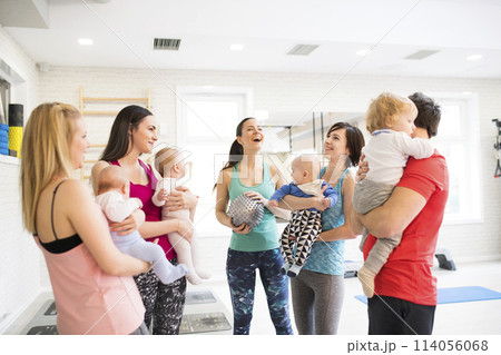 Group exercise class, mother working out with baby in gym. Moms staying active while boding with babies. New parent friends. 114056068