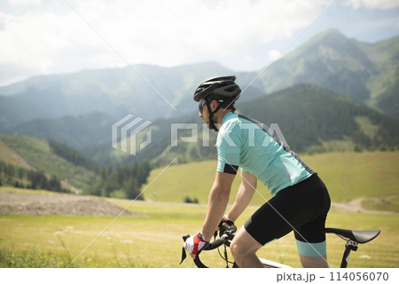 Active man riding bike across beautiful nature, feeling alive, freedom. Concept of healthy lifestyle. 114056070