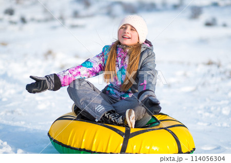 Little girl sitting and meditating on tubing snow outdors 114056304