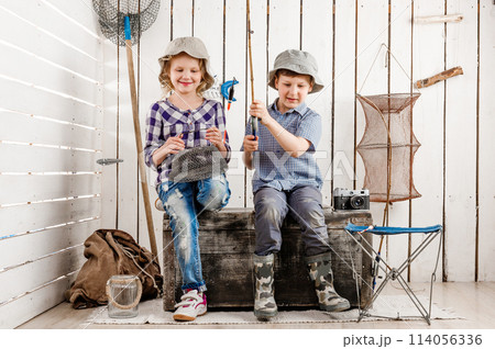 two little children sitting on big old chest with net and rod in hands 114056336