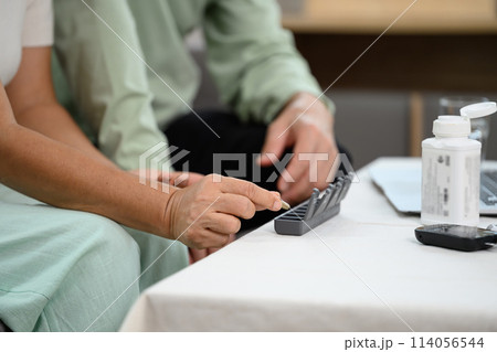 Elderly people taking pills from pillbox and vitamins for daily medication. Health care, medicine and treatment concept 114056544