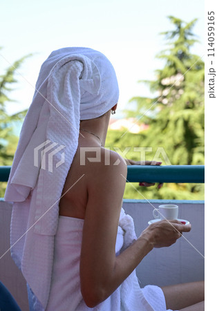 View of the reverse side of a beautiful luxury relaxing woman enjoying a cup of coffee tea on a blue sky sea outdoor background View of the reverse side of a beautiful luxury relaxing woman enjoying a cup of coffee tea on a blue sky sea outdoor background 114059165