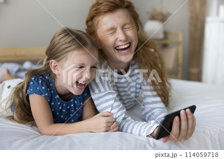 Laughing young mother watch funny video with daughter on smartphone 114059718