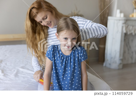 Young mother brushing long hair of little daughter Young mother brushing long hair of little daughter 114059729