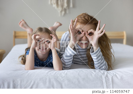 Happy mom and kid looking at camera through fingers 114059747