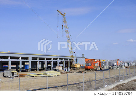 Silhouettes of tower crane against a blue sky withe clouds. House under construction. Industrial skyline 114059794