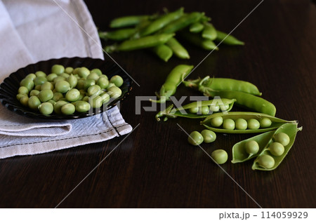 Green shoots of young peas, flowers and pods on a dark wooden background. selective focusing Green shoots of young peas, flowers and pods on a dark wooden background. selective focusing 114059929