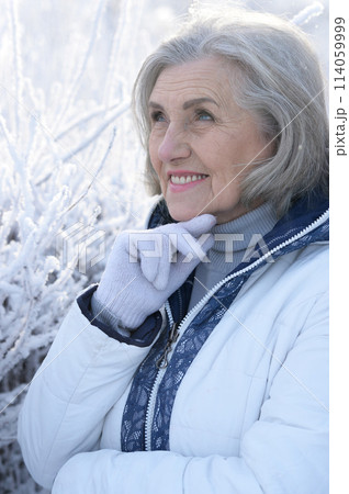 Beautiful elderly woman posing in a snowy winter park 114059999