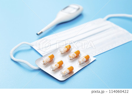 青背景にカプセル錠とマスクと体温計 青背景にカプセル錠とマスクと体温計 114060422