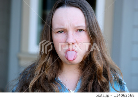 young girl angry teenager stuck out her tongue looks into the frame close-up face is dissatisfied angry so won't I said no adolescence psychological problems of communicating with children at this age 114062569