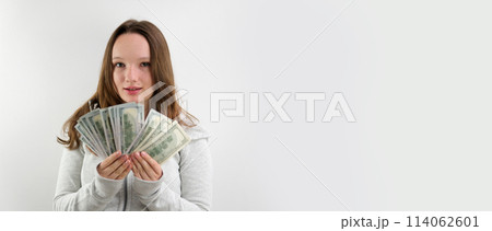 beautiful young rich girl waving a pack of 100 dollar bills like a fan, making eyes smiling on a white background, hair fluttering space for text wasting money golden youth beautiful young rich girl waving a pack of 100 dollar bills like a fan, making eyes smiling on a white background, hair fluttering space for text wasting money golden youth 114062601