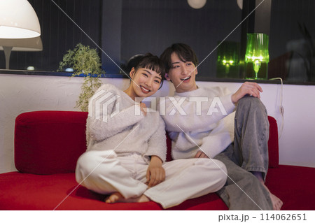 並んでソファに座る笑顔の若い男女 114062651