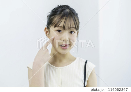 舌を出して指を頬に当ててポーズを取る小学生の女の子のポートレート 114062847