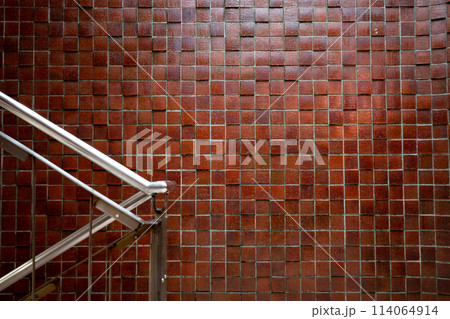赤茶色のタイルの壁と階段の手すり 114064914