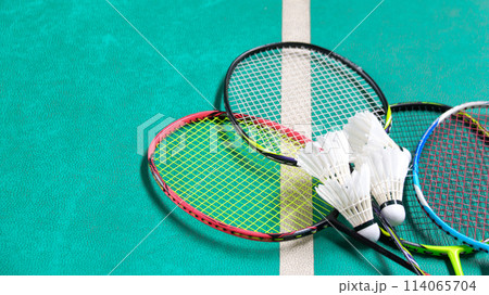 White badminton shuttlecocks and badminton rackets on green floor indoor badminton court 114065704
