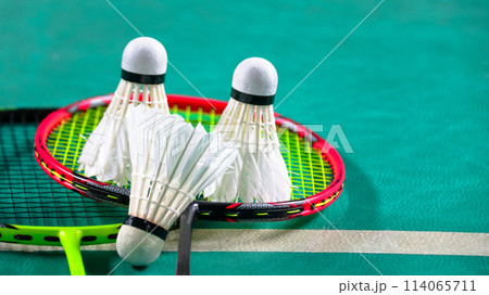 White badminton shuttlecocks and badminton rackets on green floor indoor badminton court soft and selective focus on shuttlecocks and the rackets 114065711