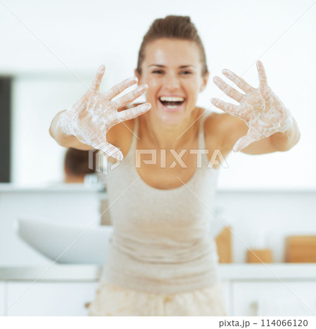 Happy young woman showing soapy hands Happy young woman showing soapy hands 114066120