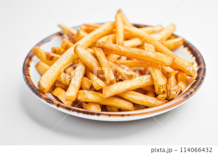 Delicious looking French fries. Salted potato fry in a white bowl on a white isolated background. Pile of frites. Golden homemade deep fried salty french fries serving on a plate. Very good chips 114066432