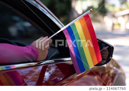 Hand holding a pride flag out the car window 114067760