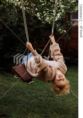 A young girl is swinging on a swing in a backyard A young girl is swinging on a swing in a backyard 114068001