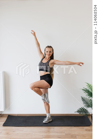 Young woman practicing balance exercises in a bright room Young woman practicing balance exercises in a bright room 114068504