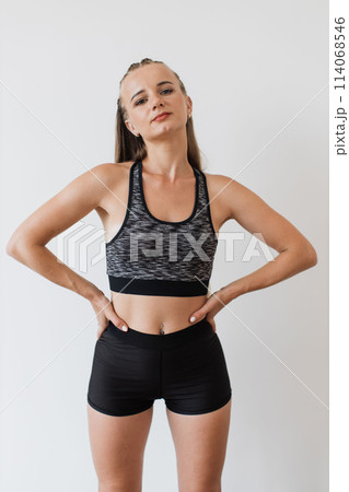Confident young woman poses in fitness attire indoors Confident young woman poses in fitness attire indoors 114068546