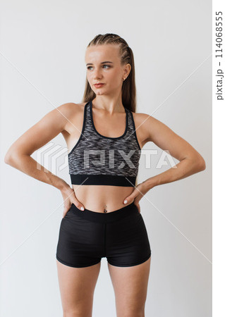 Confident young woman poses in fitness attire indoors Confident young woman poses in fitness attire indoors 114068555