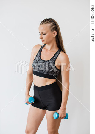 Young Woman Exercising with Dumbbells in Fitness Attire 114069063