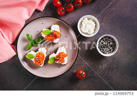 Appetizing crostini on rye bread in the shape of a heart with ricotta and tomatoes top view 114069753