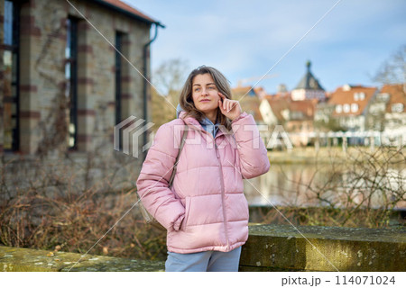 Young beautiful pretty tourist girl in warm hat and coat with backpack walking at cold autumn in Europe city enjoying her travel in Bietigheim-Bissingen, Deutschland. Outdoor portrait of young tourist Young beautiful pretty tourist girl in warm hat and coat with backpack walking at cold autumn in Europe city enjoying her travel in Bietigheim-Bissingen, Deutschland. Outdoor portrait of young tourist 114071024