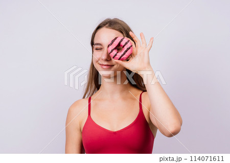 Young cute sport woman eating a donut cake in studio background 114071611